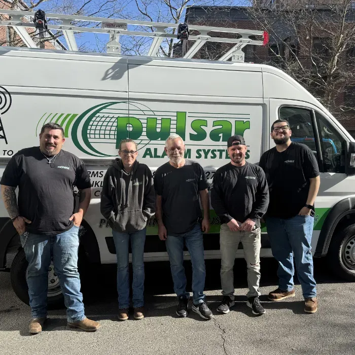 Pulsar technicians standing in front of a Pulsar Alarm Systems service van